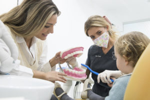 dentista infantil atendiendo un niño y enseñando como cepillar sus dientes