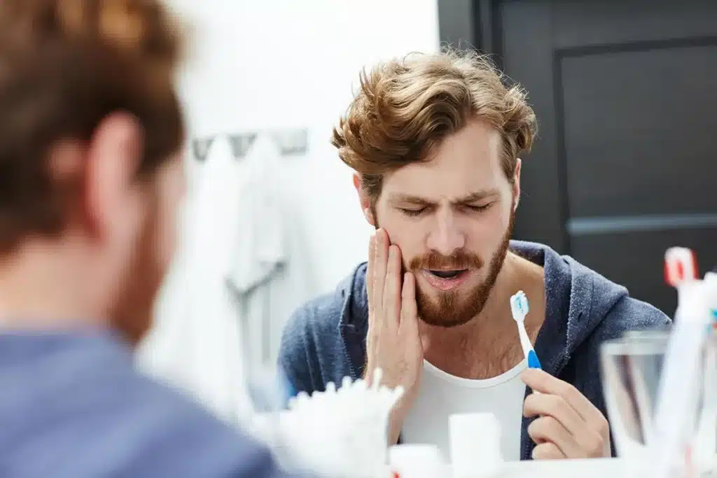 hombre lavandose los dientes sensibles con dolor