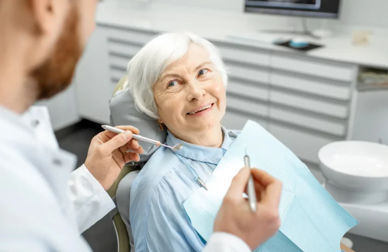 mujer mayor de la tercera edad en una consulta dental mirando al dentista