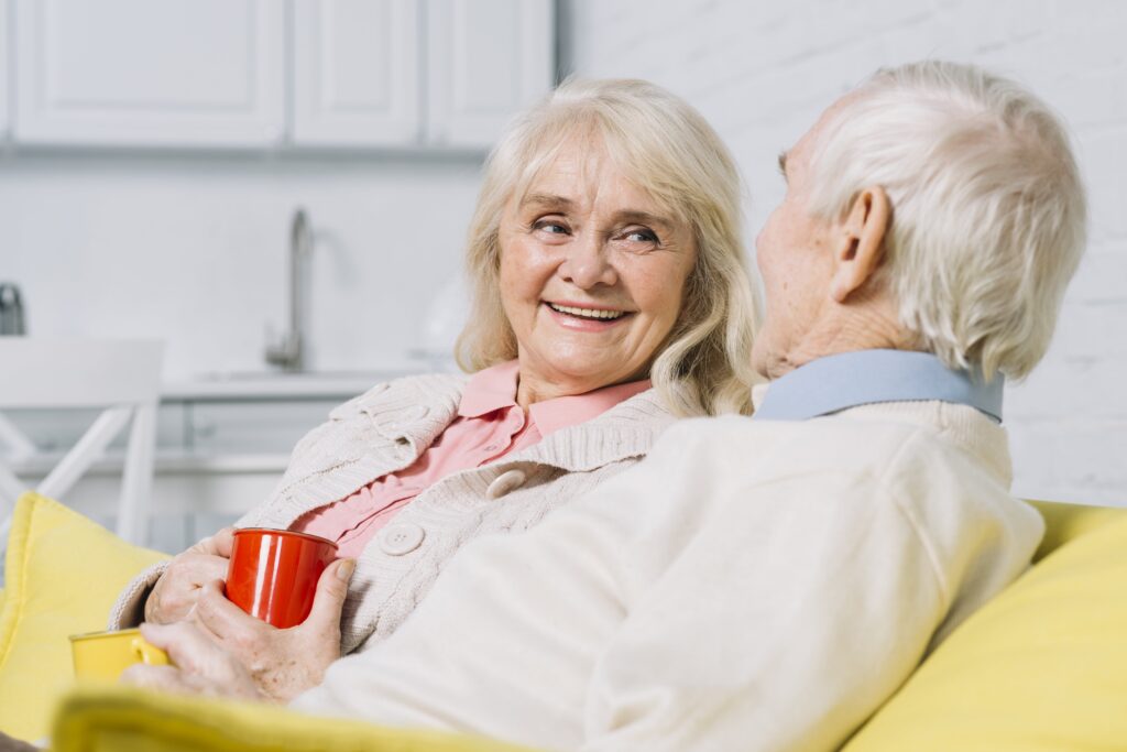 Pareja de ancianos mirándose a los ojos. La mujer mostrando una sonrisa espléndida.